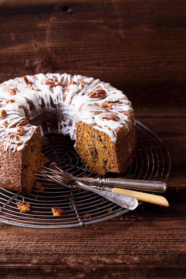 Pumpkin cake with pecan nuts on a cooling rack