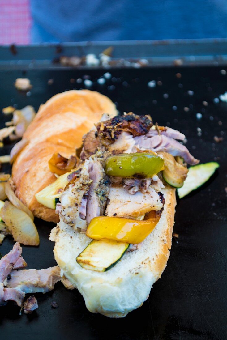 A street food sandwich with yellow pepper, courgette and meat