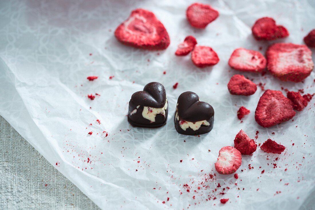 Vegan dark chocolate heart-shaped pralines, filled with vanilla cream and freeze-dried strawberries