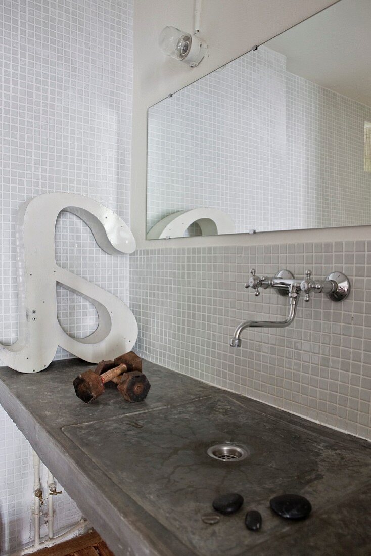 Concrete washstand, vintage-style wall-mounted taps and mirror in bathroom with white mosaic wall tiles