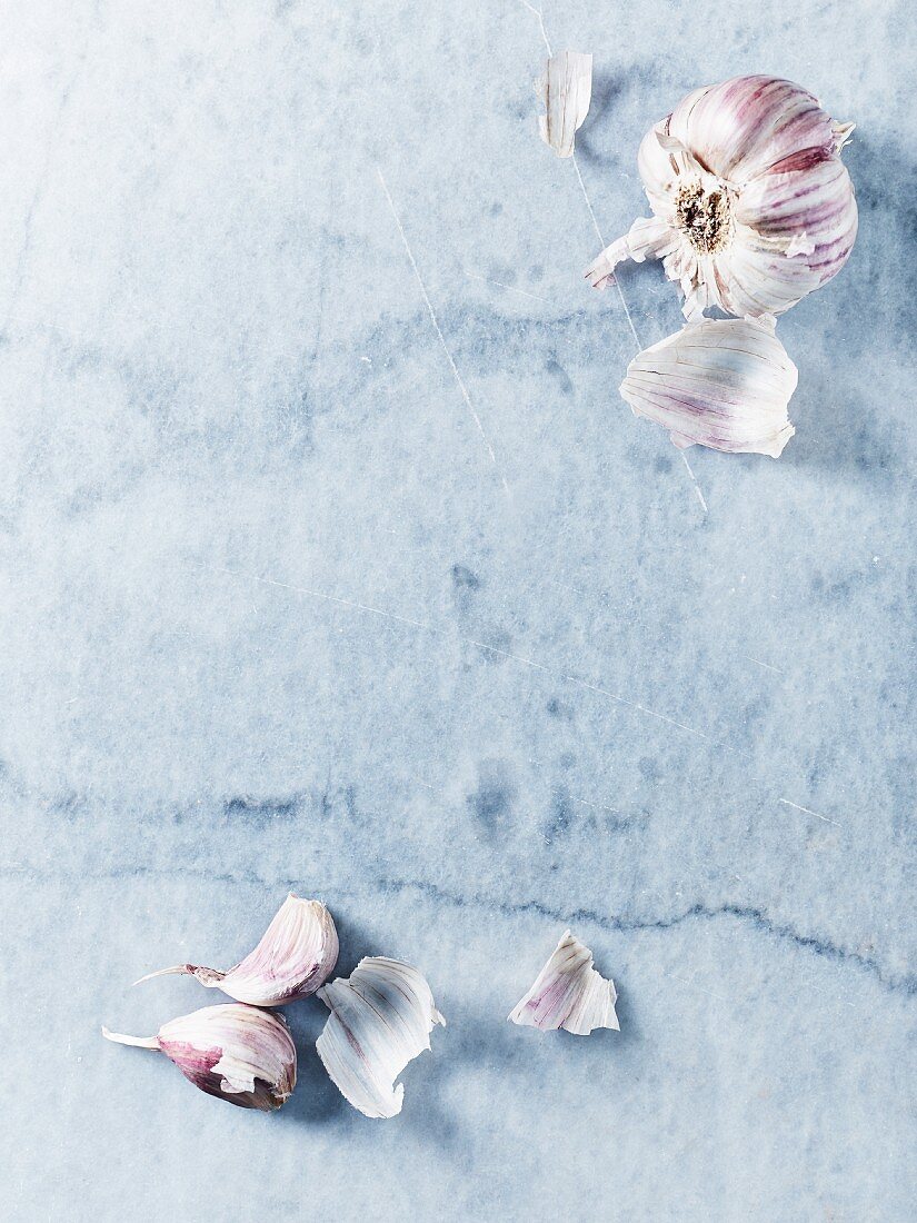 A garlic bulb and cloves on a marble background