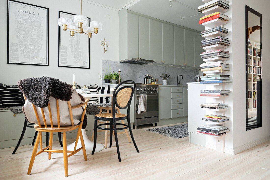 Dining area, fitted kitchen and vertical bookcase in doorway in open-plan interior