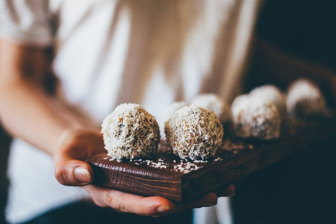 Frau hält Tablett mit Bliss Balls