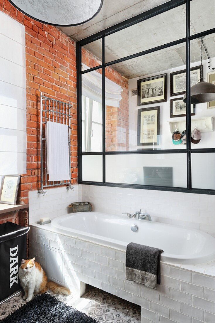 Glass and steel partition above bathtub in bathroom