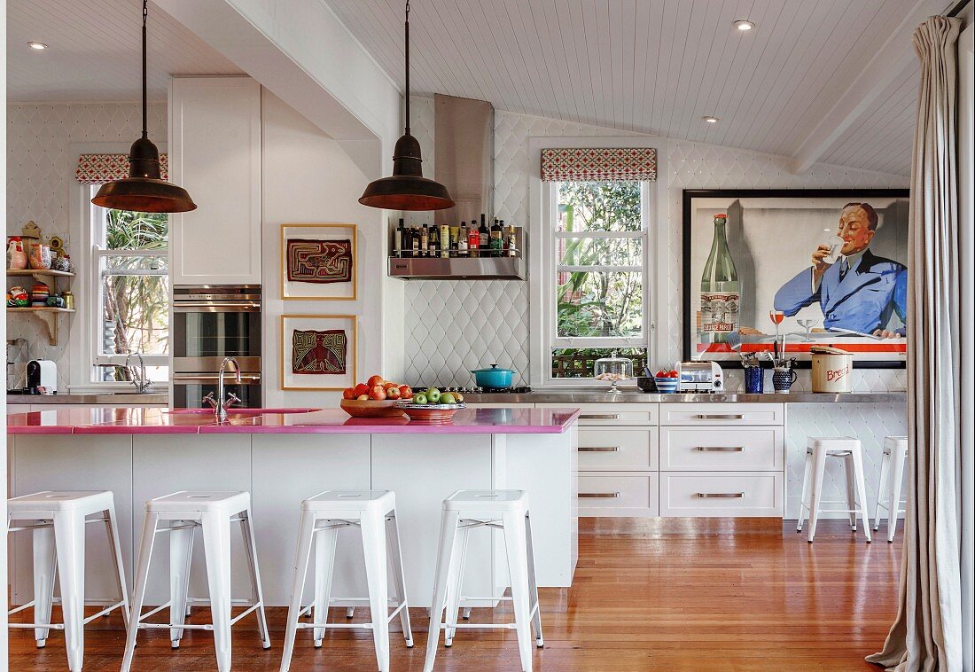 Pinkfarbene Küchenarbeitsplatte auf Küchentheke mit Barhocker in offener Küche mit Retro-Flair