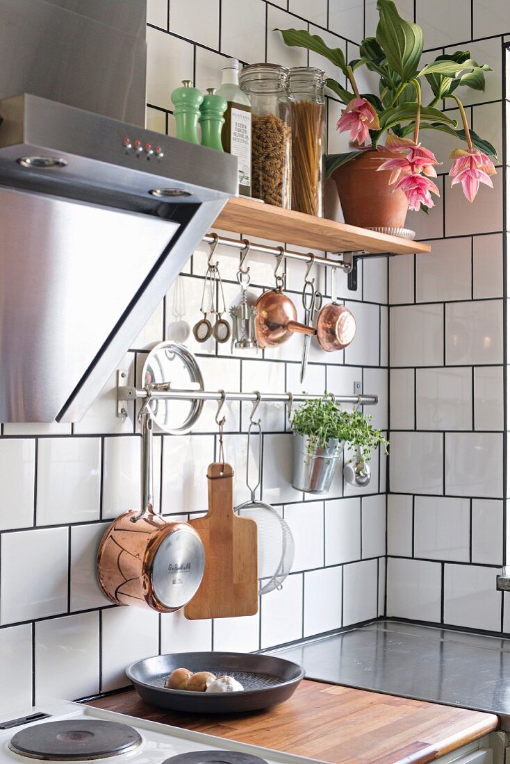 Utensils hung on tiled wall in corner of kitchen