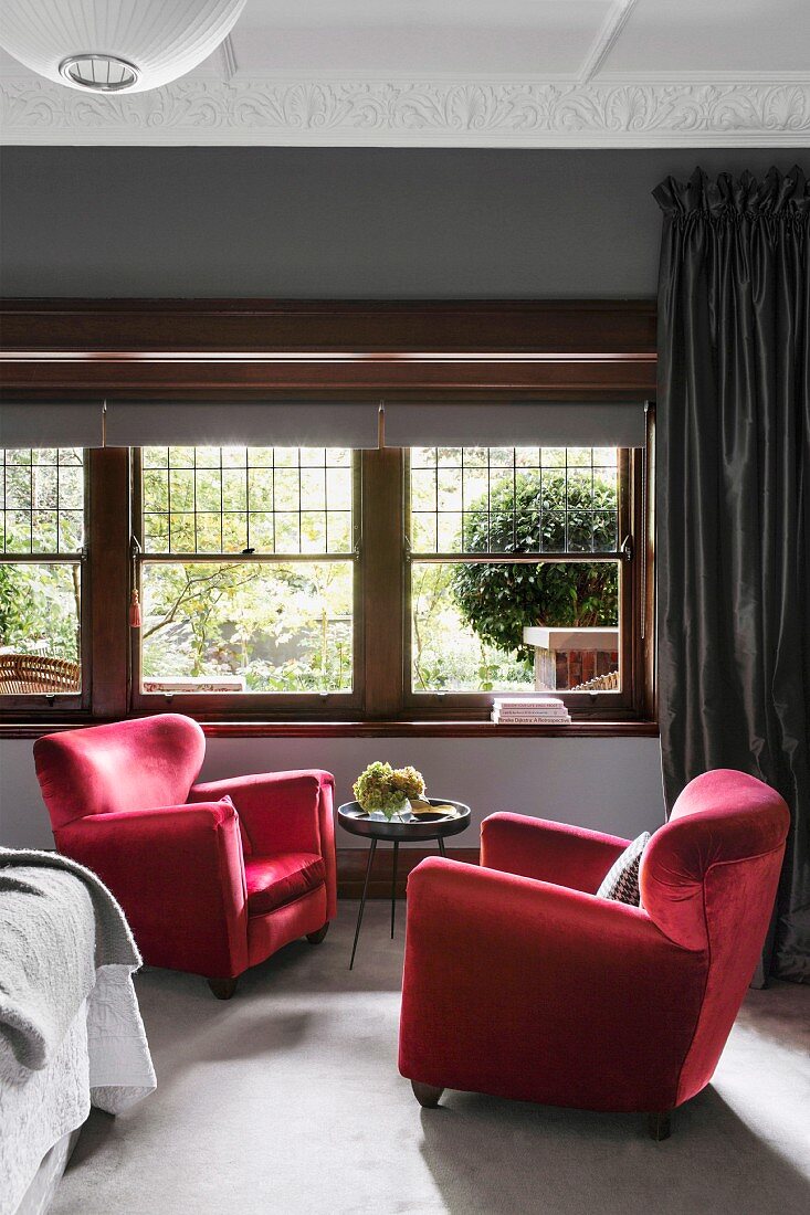 Two red velvet armchairs in the bedroom in front of the window