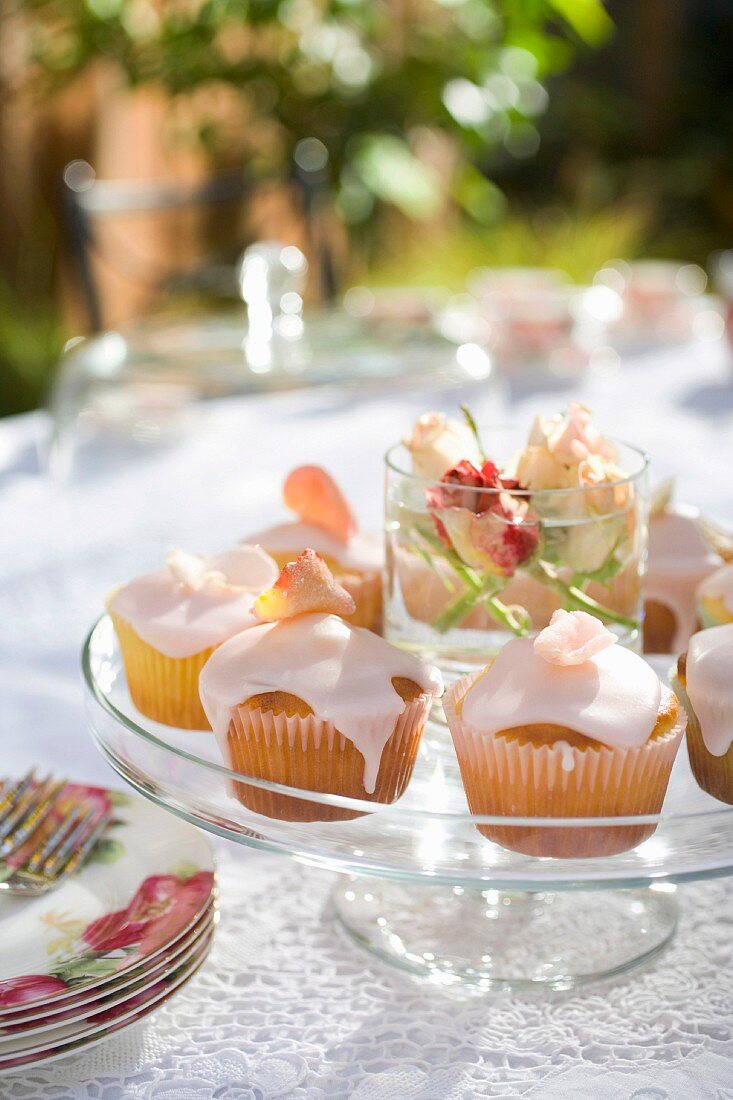 Rosen-Cupcakes auf frühlingshaftem Tisch im Freien