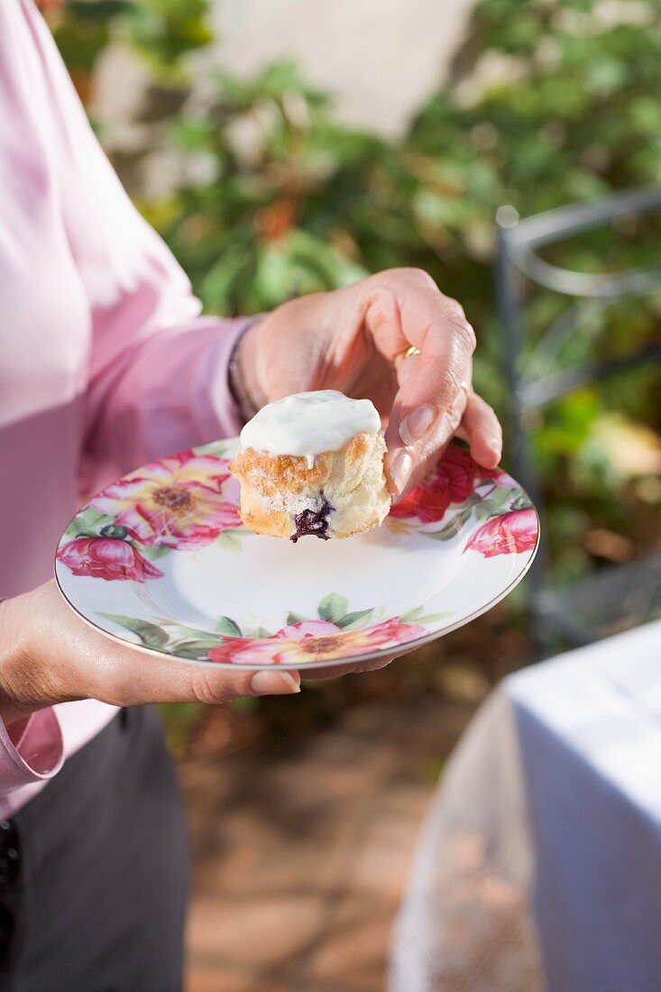 Frau hält Teller mit Blaubeer-Scone