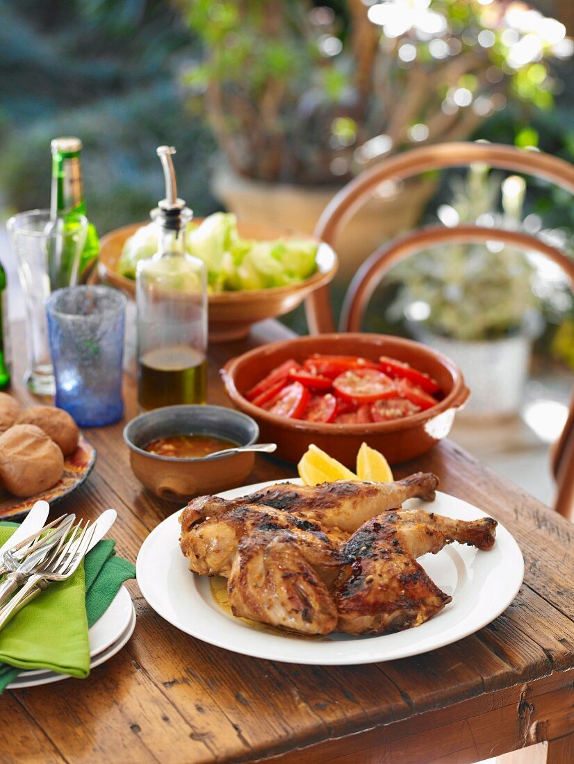 Knoblauchhähnchen mit Tomatensalat (Portugal) auf Tisch im Freien