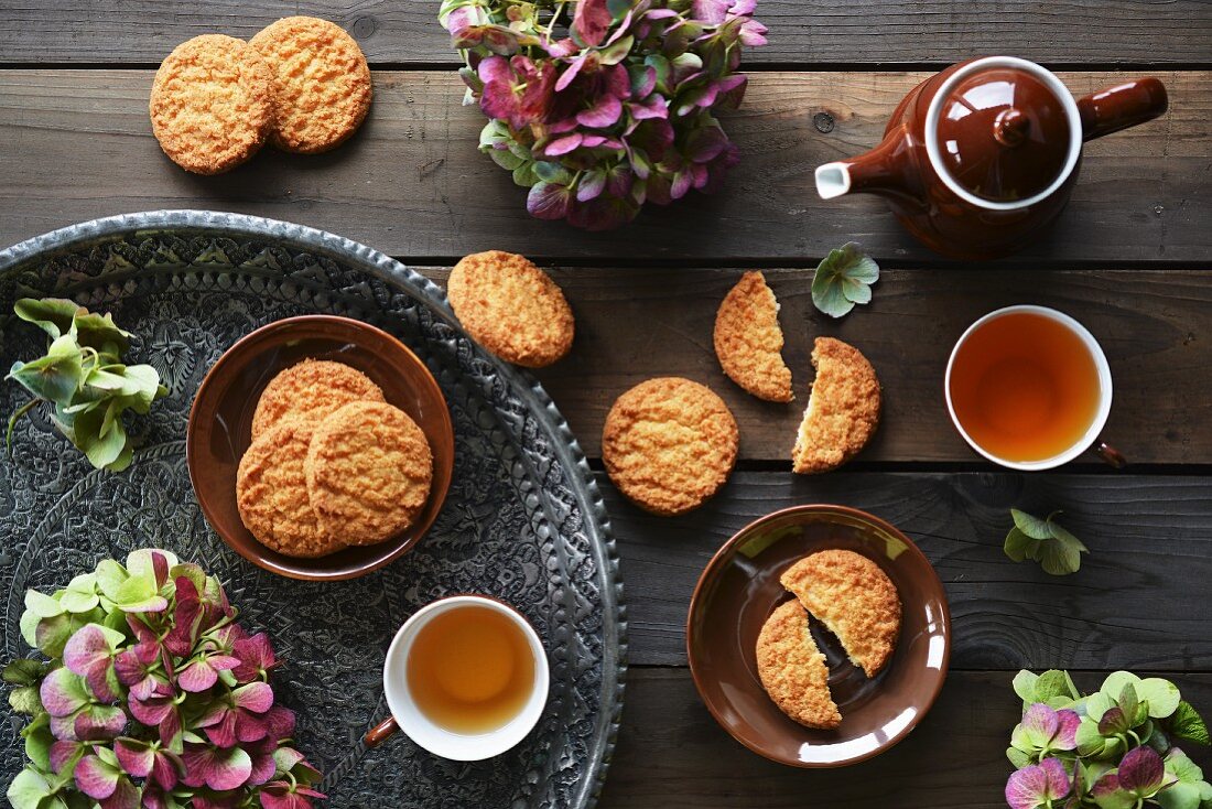 Kokoskekse und Tee auf Tablett, mit frischen Blumen dekoriert