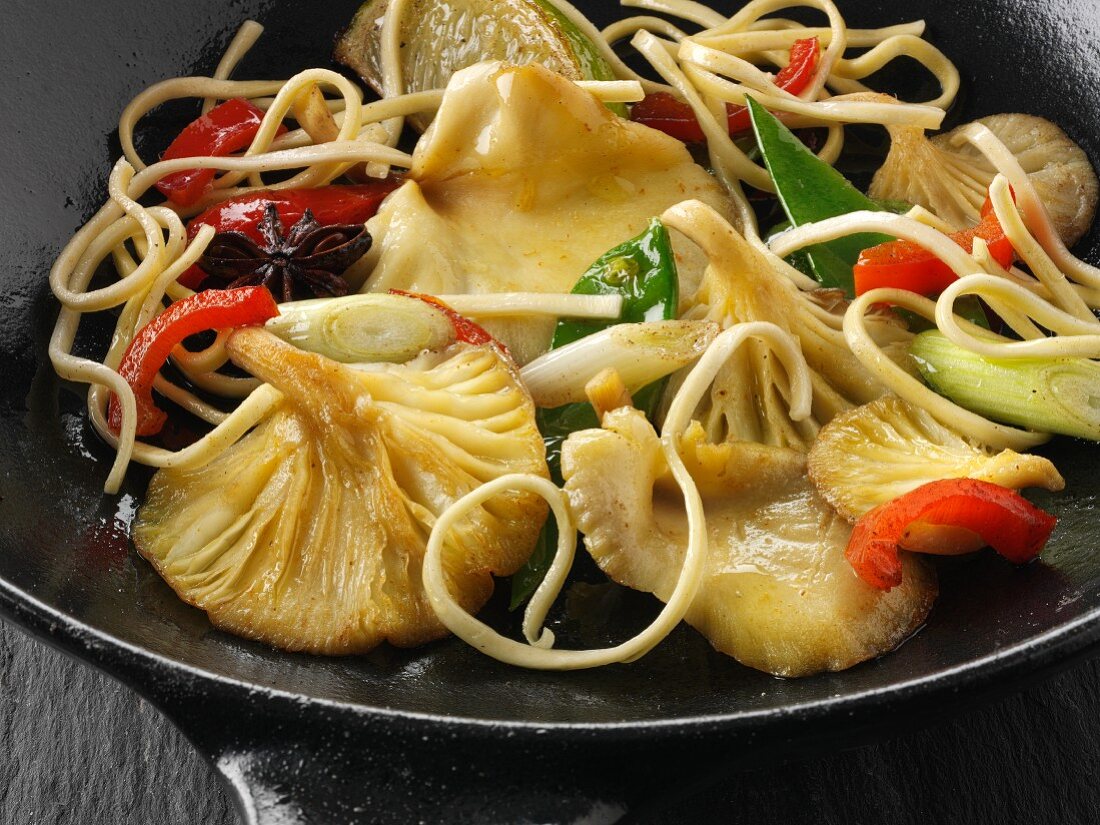 Yellow Oyster mushroom stir fry being cooked with noodles, mange tout, red pepper, spring onions and start anise