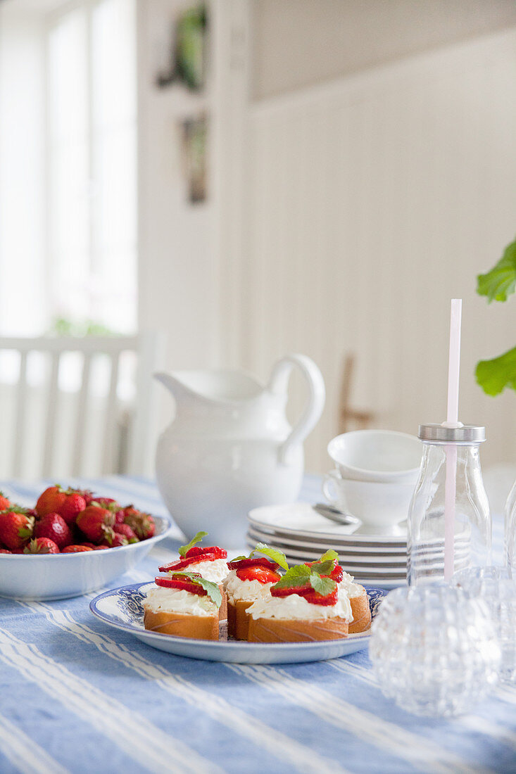 Brote mit Frischkäse und Erdbeeren auf dem gedeckten Tisch