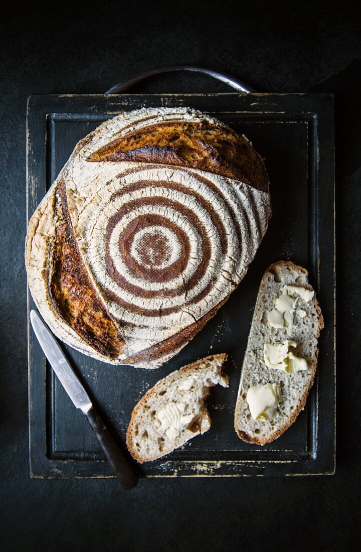 Frisch gebackenes Sauerteigbrot und mit Butter bestrichene Brotscheiben