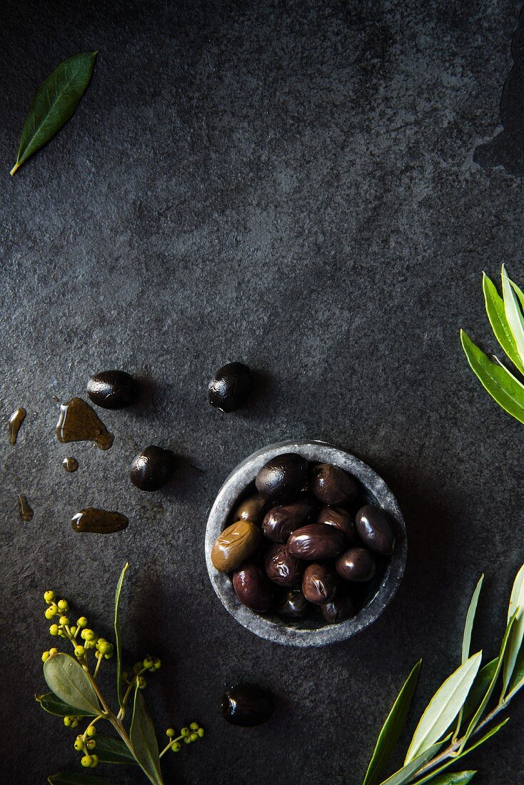 A bowl of olives with olive leaves