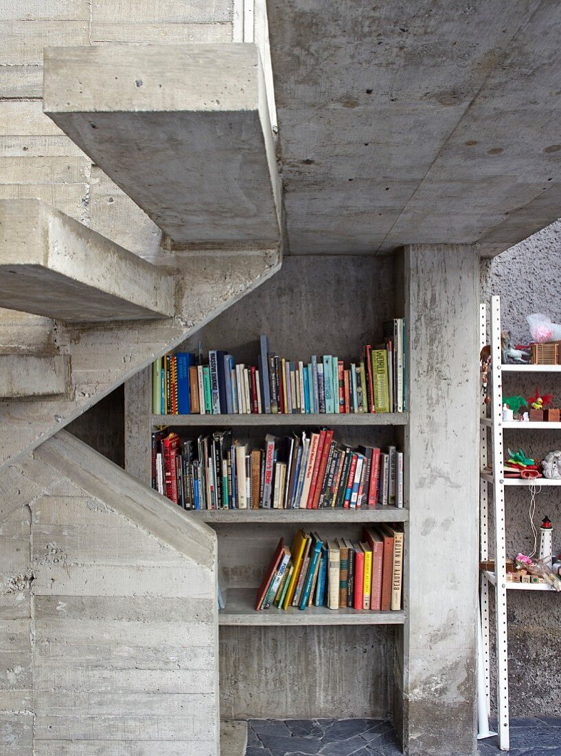 Bookcase below staircase in concrete house