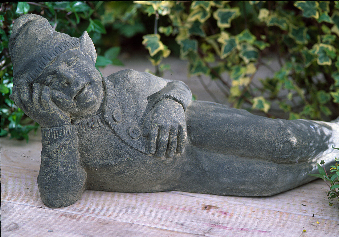 Lying garden gnome made of cement