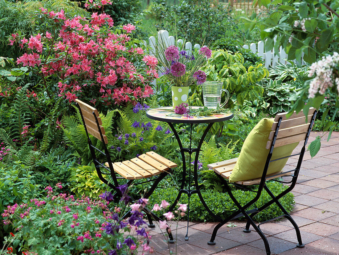 Seating area by a bed with azaleas and ferns