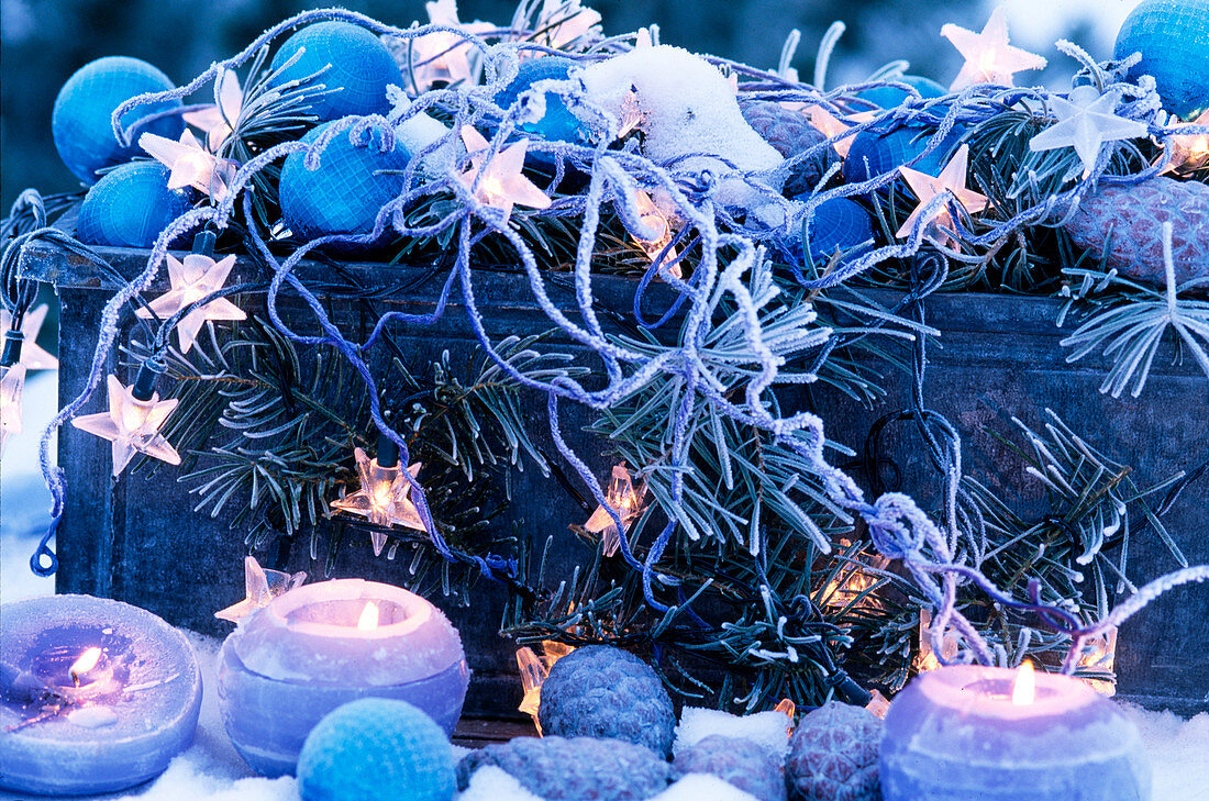 Tin box with blue balls, starry lights, branches and candles