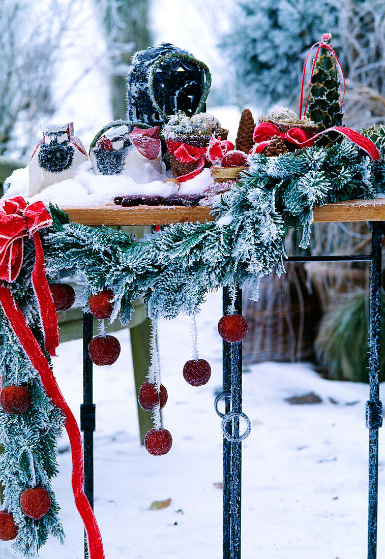 Table with advent decoration, fir branch garland, lantern and apples