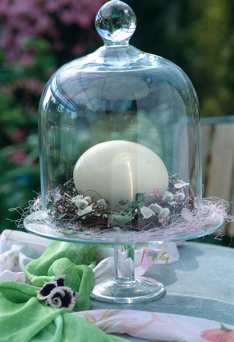 Glass bowl with duck egg in nest of twigs, ivy leaves