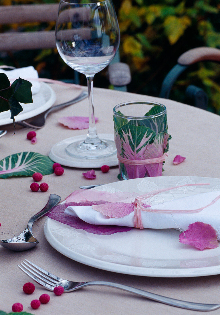 Tischdeko: Serviette mit Brassica (Zierkohlblättern) dekoriert, Windlicht mit Blättern