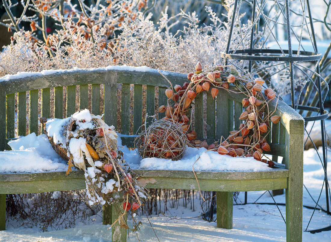 Garden bench in winter decorated with wreath of physalis