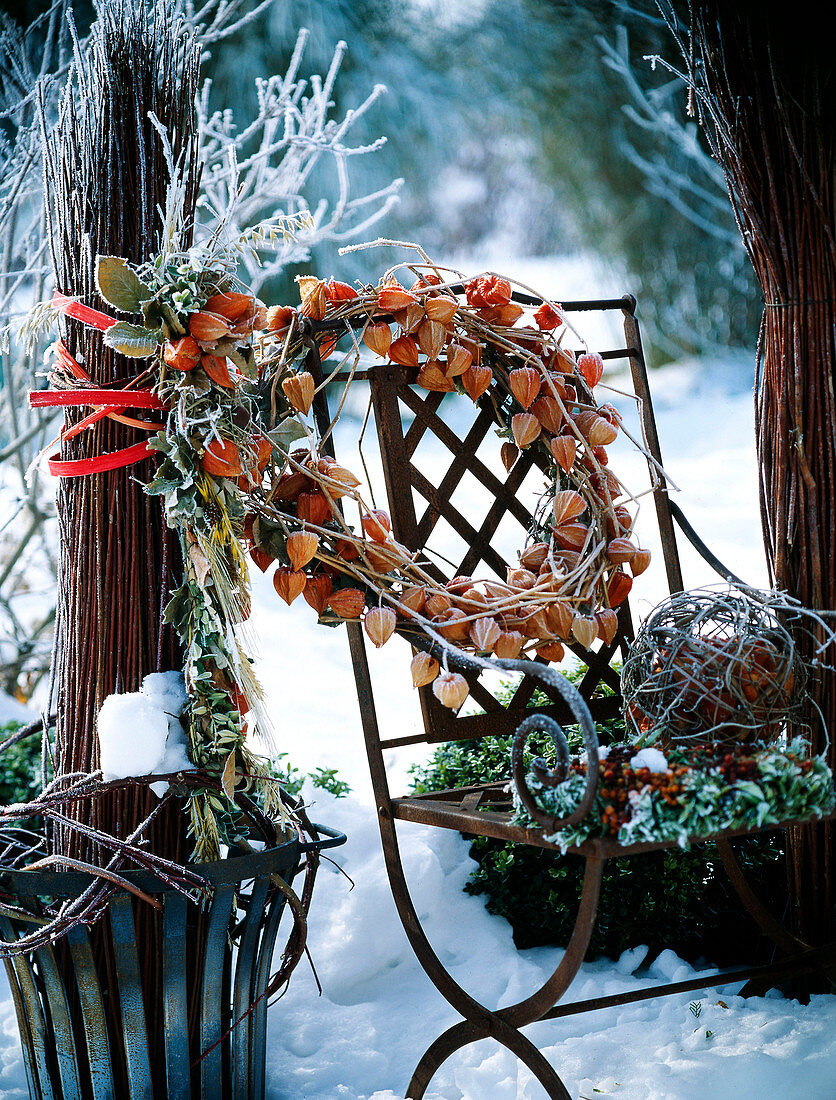 Iron chair decorated with hoarfrost with wreath of physalis (lampion flower), willow ball