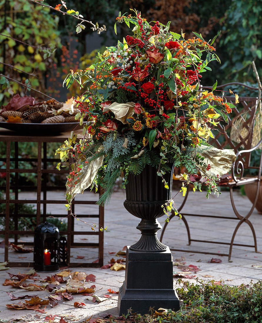 Bouquet in iron vase with roses, holly, dendranthema (autumn chrysanth)