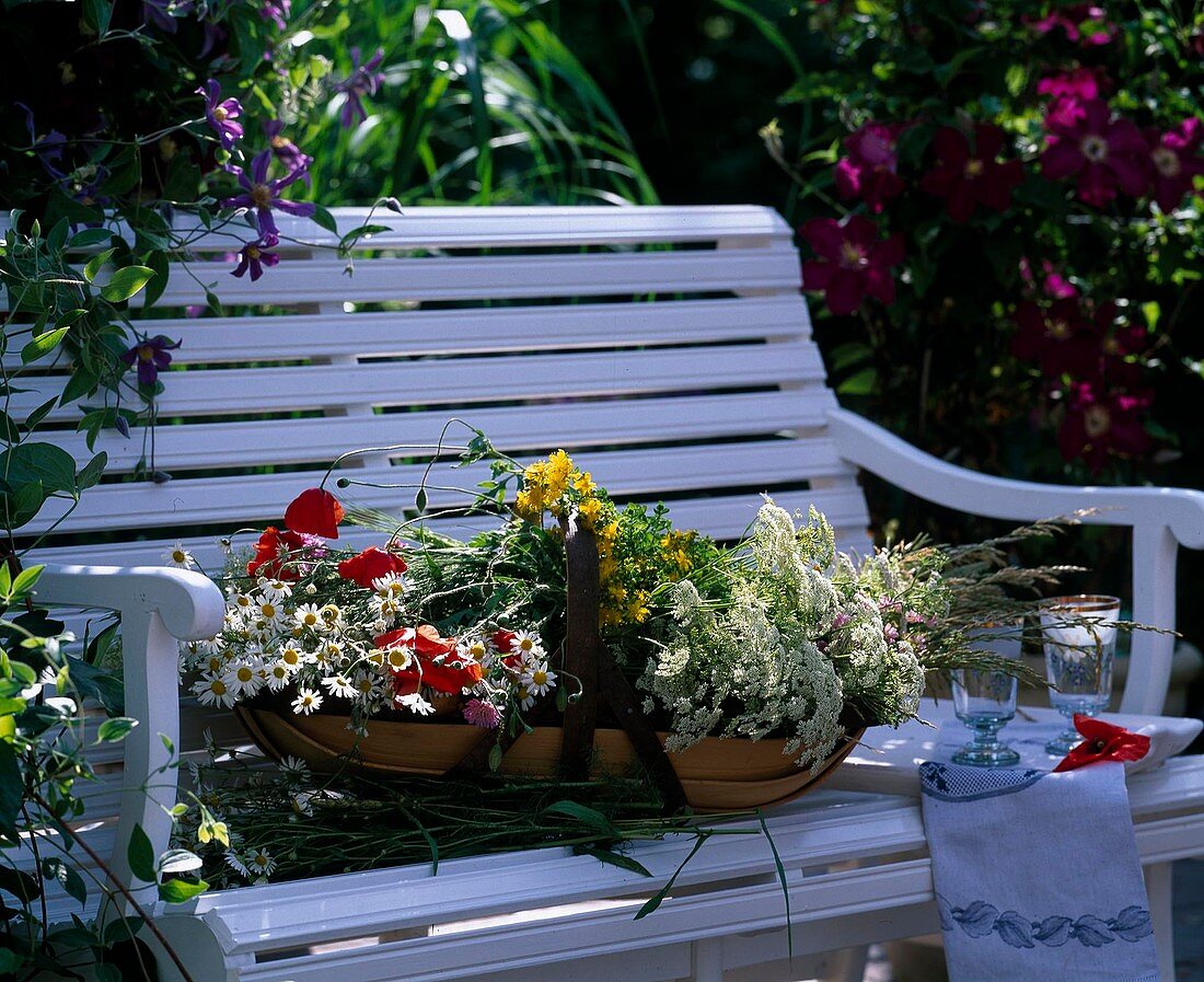 Wooden bench with basket and freshly cut meadow flowers