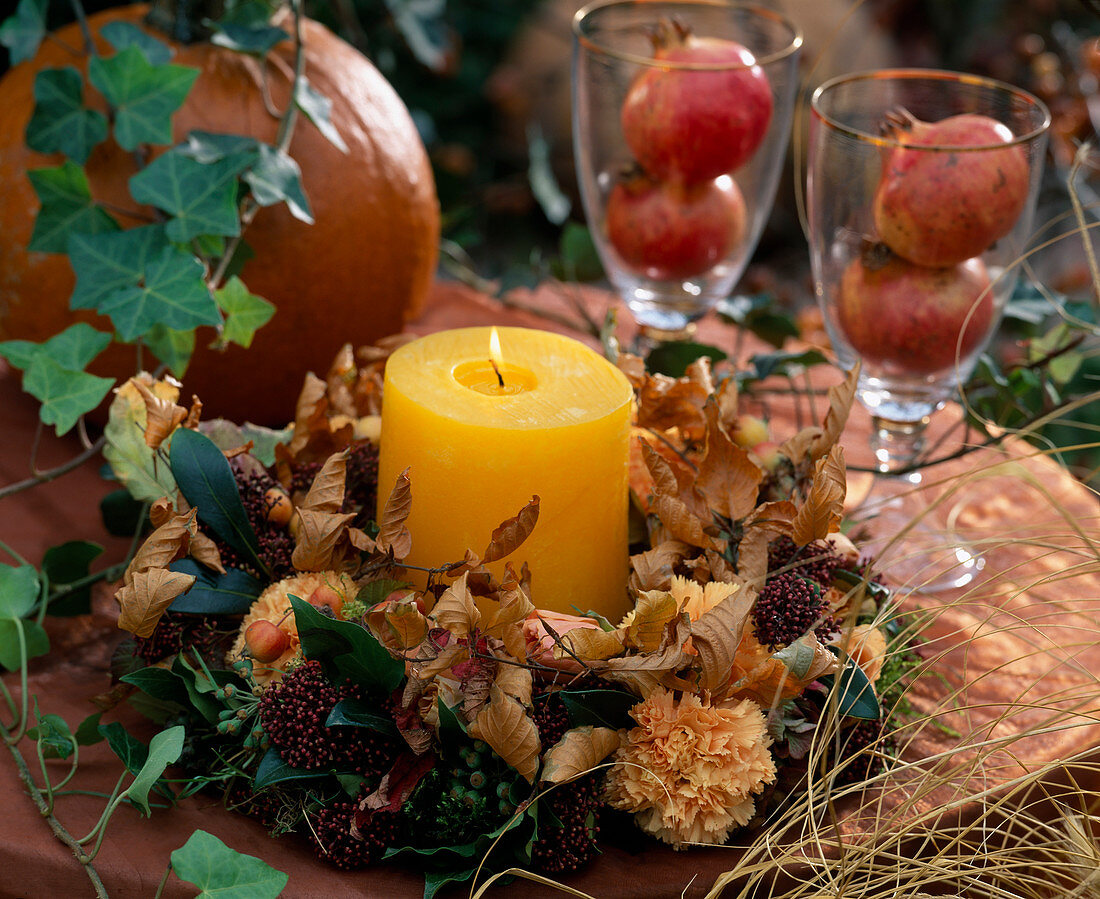 Candle with wreath of Carpinus (hornbeam), Skimmia, Dianthus (carnations), Hedera (ivy)