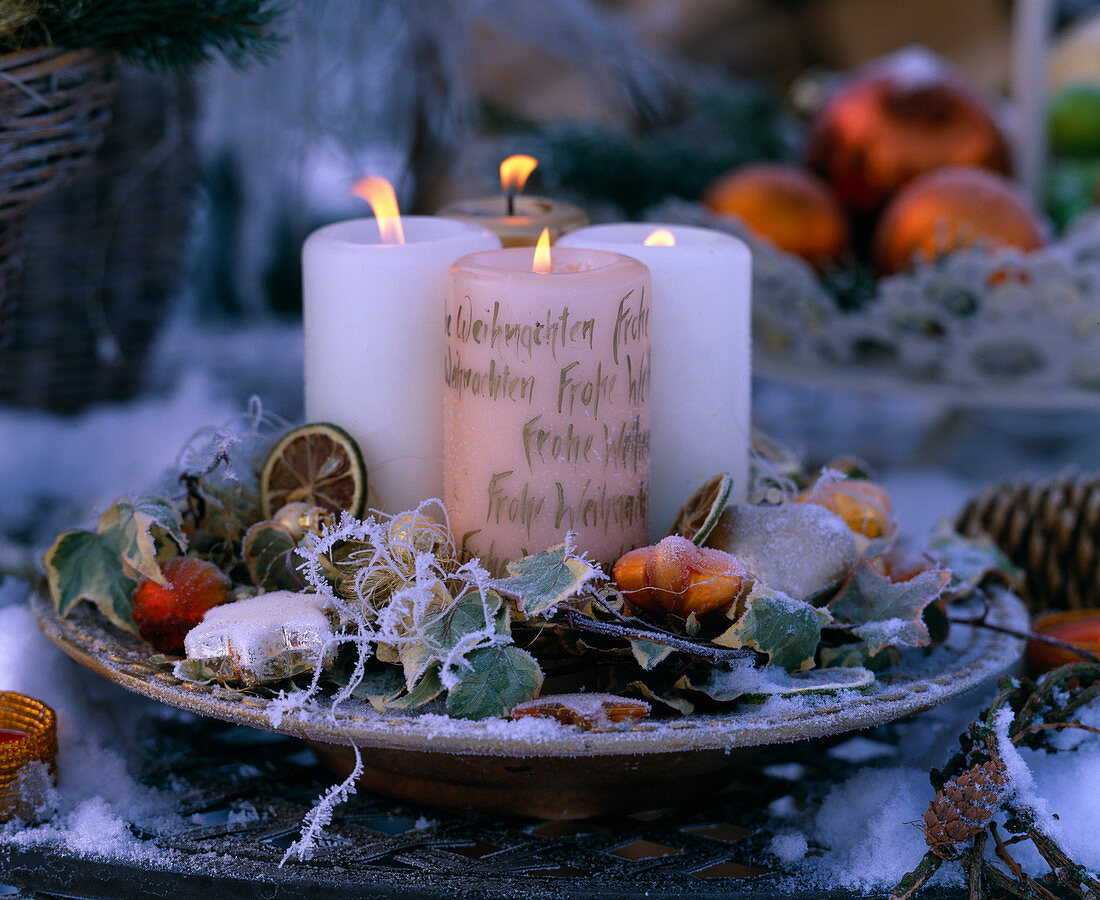 Plate with 4 candles, slices of lime, ivy and Christmas tree decorations as decoration