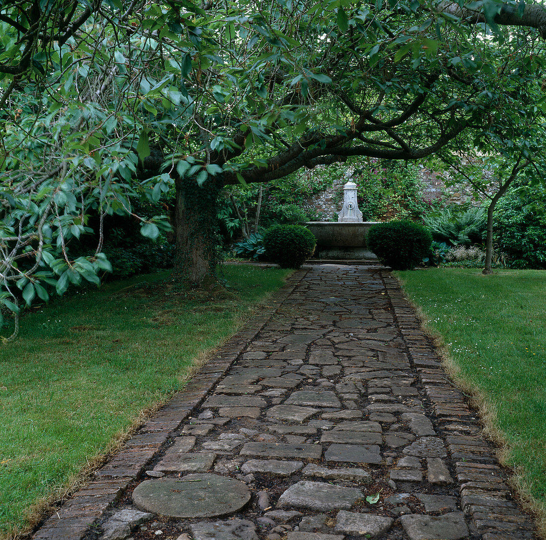 Straight path of various stones with lawn edge, view of fountain