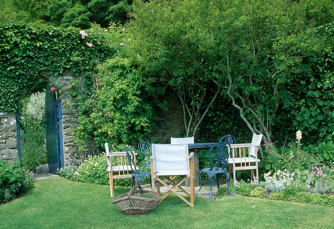 Seating area by the flowerbed, wall with Hedera (ivy), open garden door