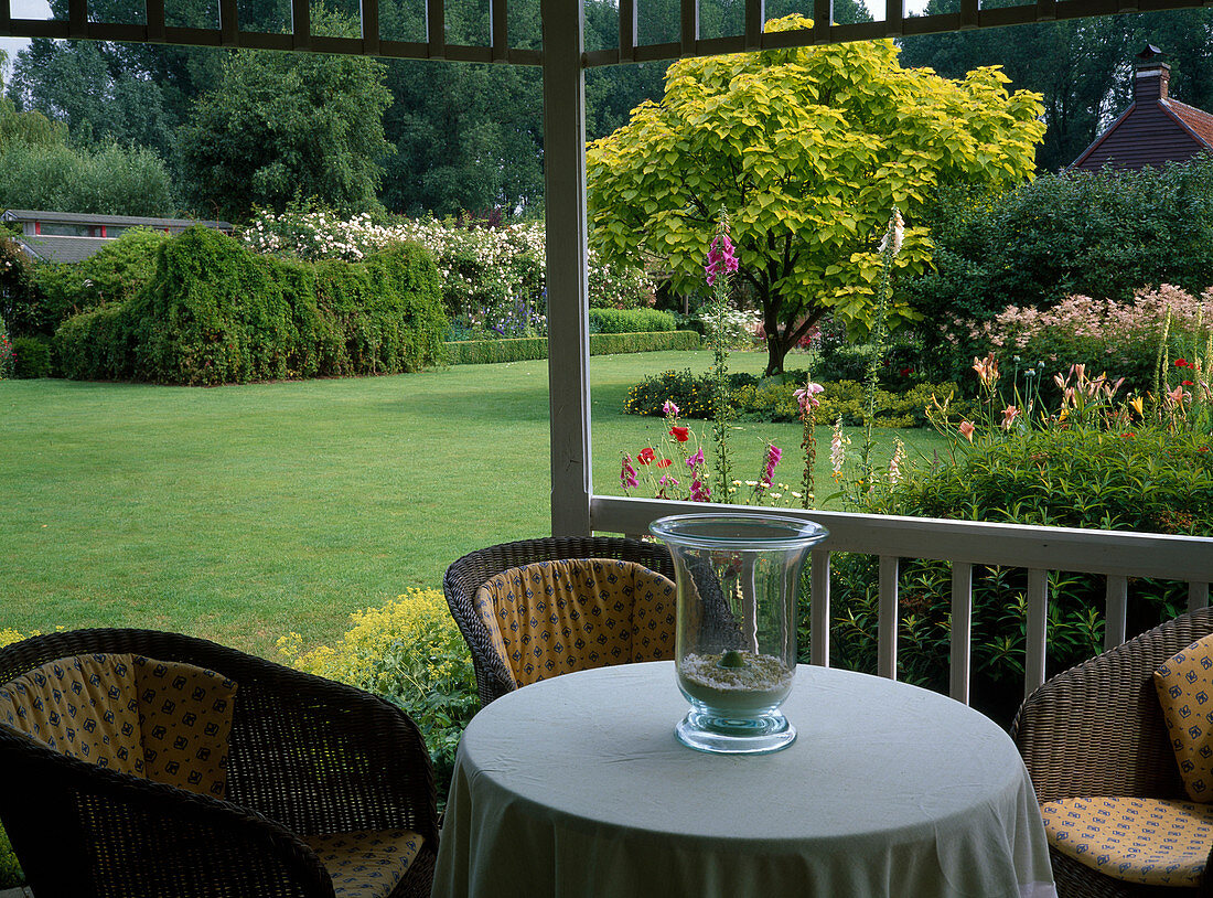 Blick vom Sitzplatz einer überdachten Gartenlaube auf den Garten
