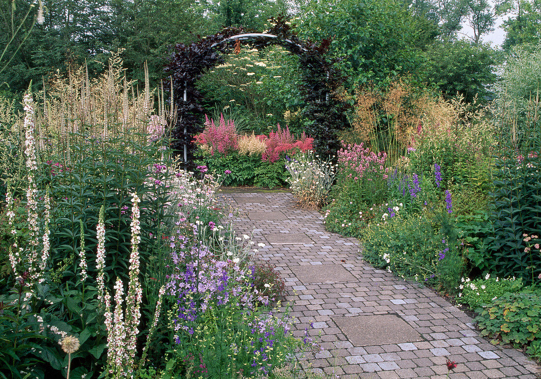 Weg mit Beton-Steinen und Platten gepflastert in reich bepflanztem Garten