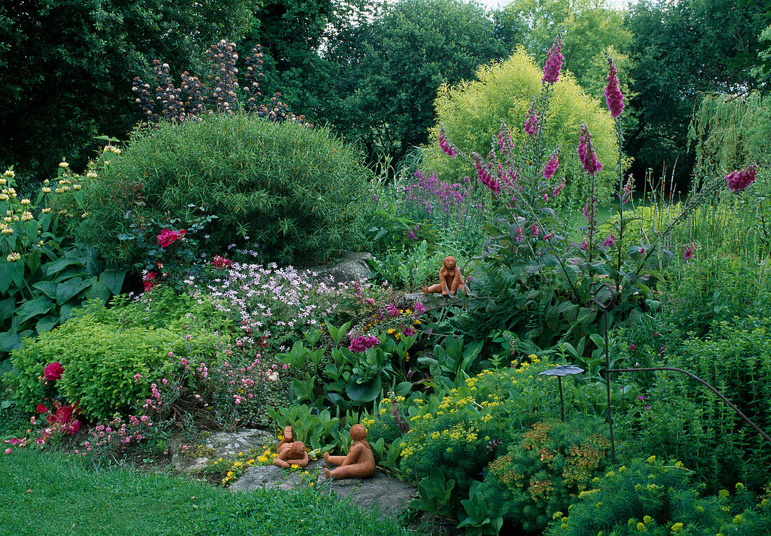 Sommerbeet mit Digitalis (Fingerhut), Oregano (Origanum vulgare), Euphorbia cyparissias (Zypressenwolfsmilch), Phlomis (Brandkraut), Tonfiguren als Deko