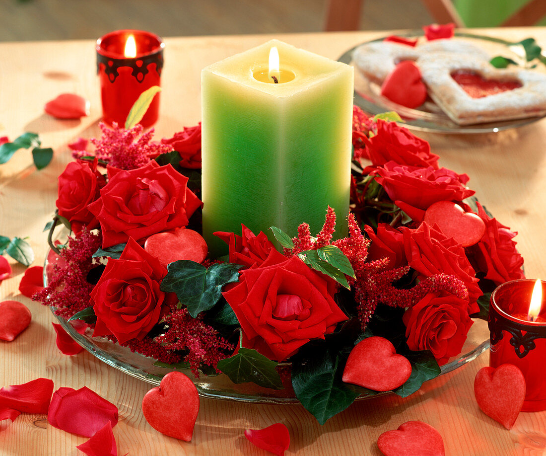 Green candle in wreath of red roses