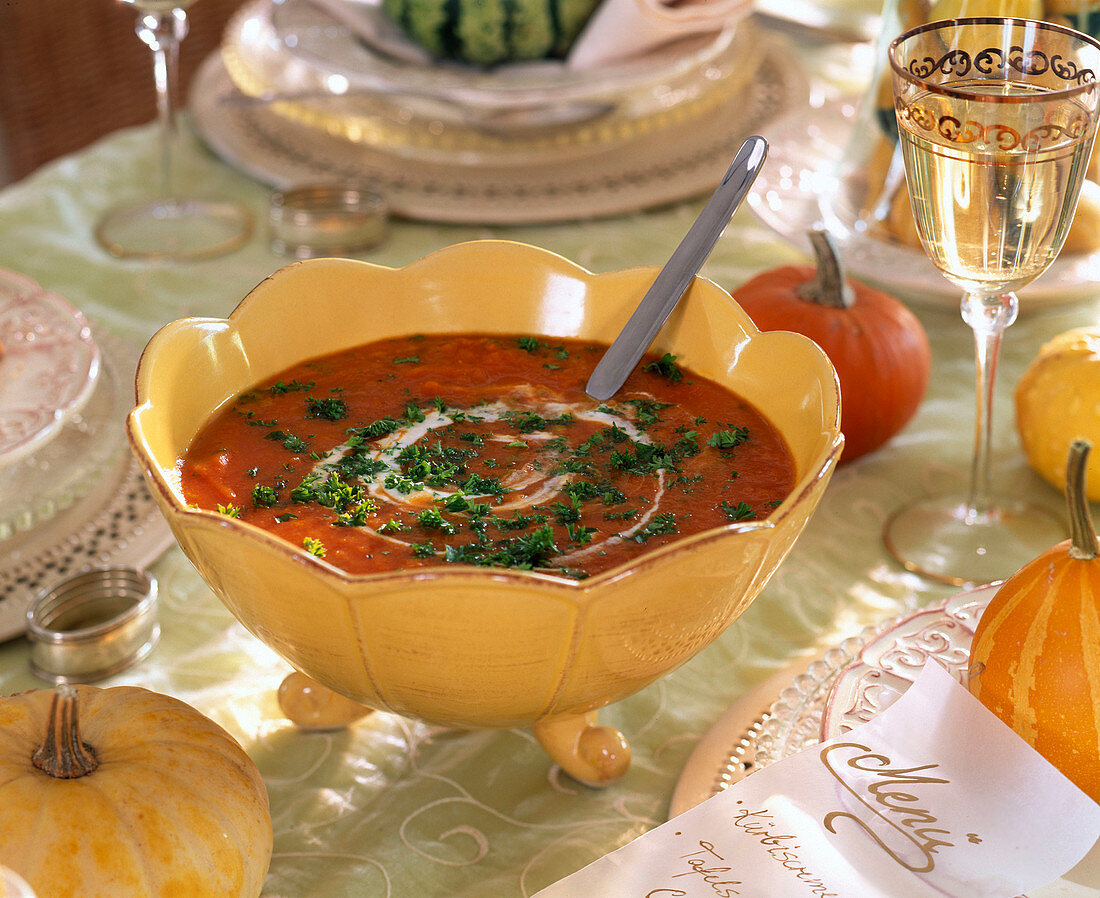 Gelbe Suppenterrine mit Kürbissuppe, dekoriert mit Petersilie und Sahne
