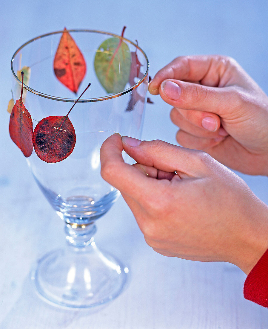 Autumn leaves on gold wire around glass with candles (2/3)