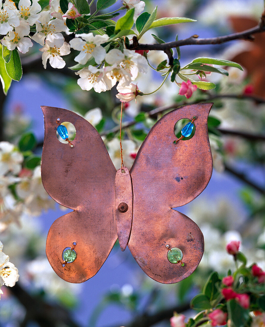 Flower shaped copper pendant on branch of malus (apple)