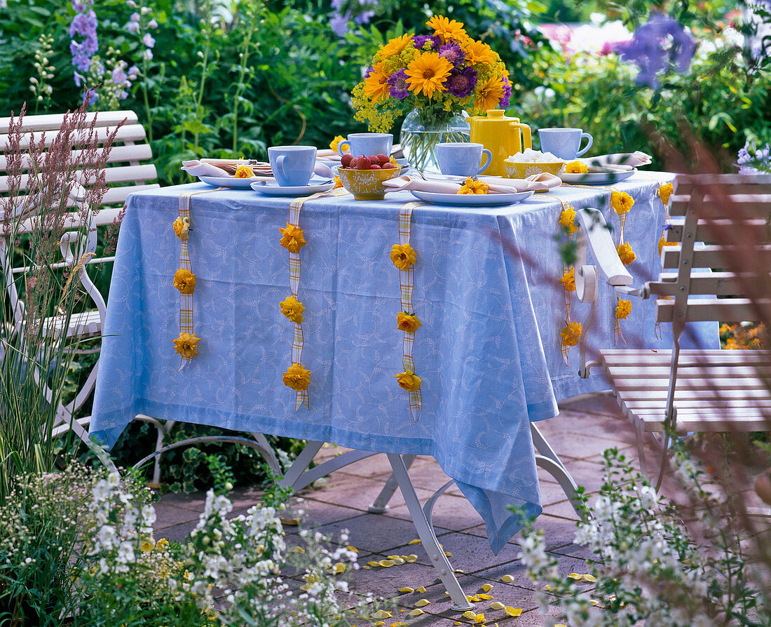 Flowers and leaves of Rosa (roses, yellow) on ribbons at the side of table