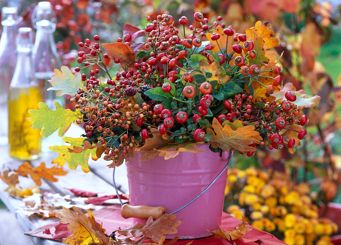 Bouquet of pink (rose hips), Quercus (oaks) in pink bucket on bench