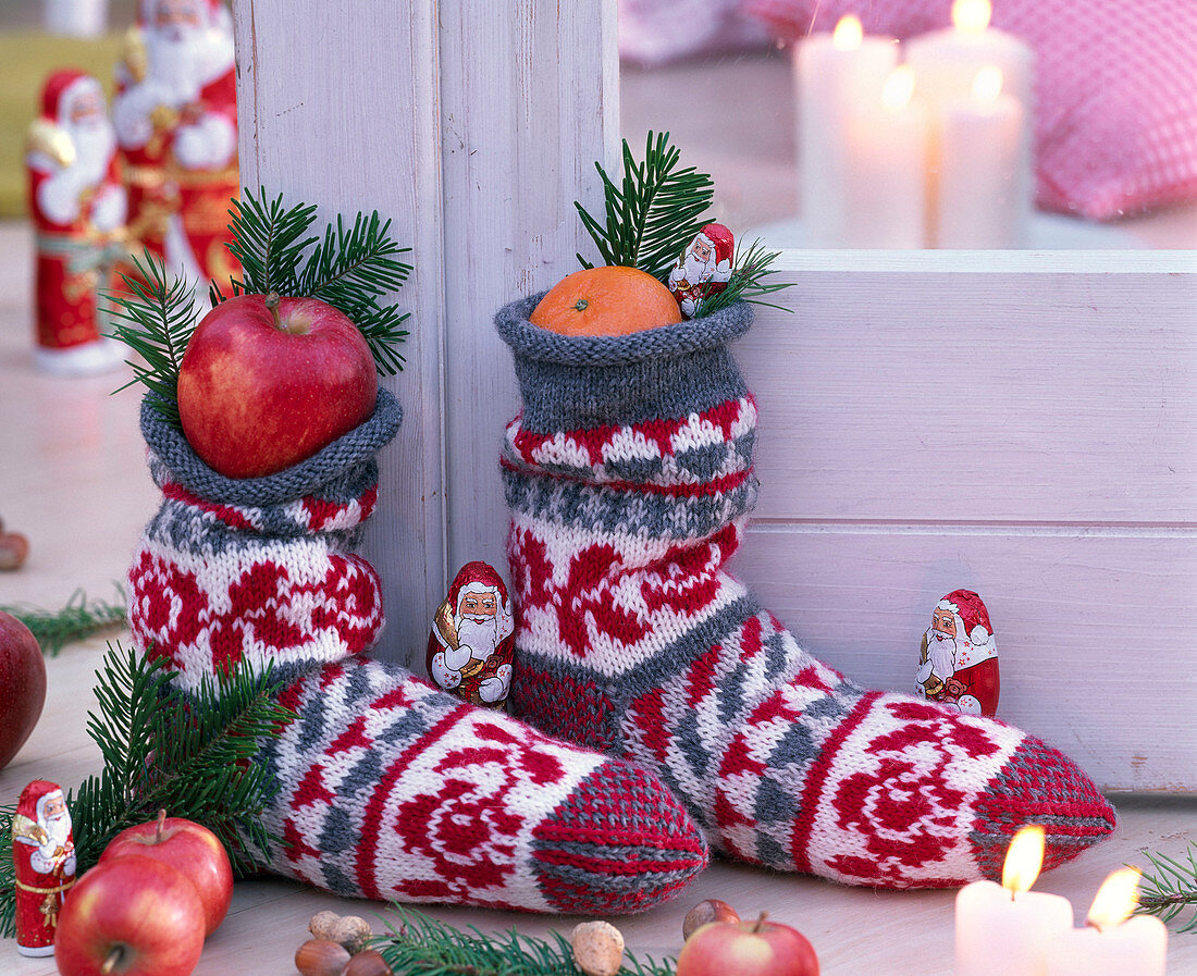 Nikolaus-Dekoration mit selbstgestrickten Socken gefüllt mit Malus (Äpfeln)