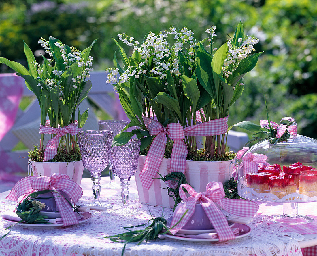 Convallaria majalis (lily of the valley) in pink and white metal vessels