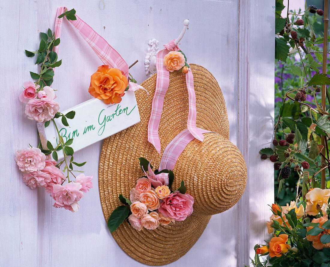 Rosa (Rosen) an Haken und an Strohhut, Schild 'Bin im Garten'