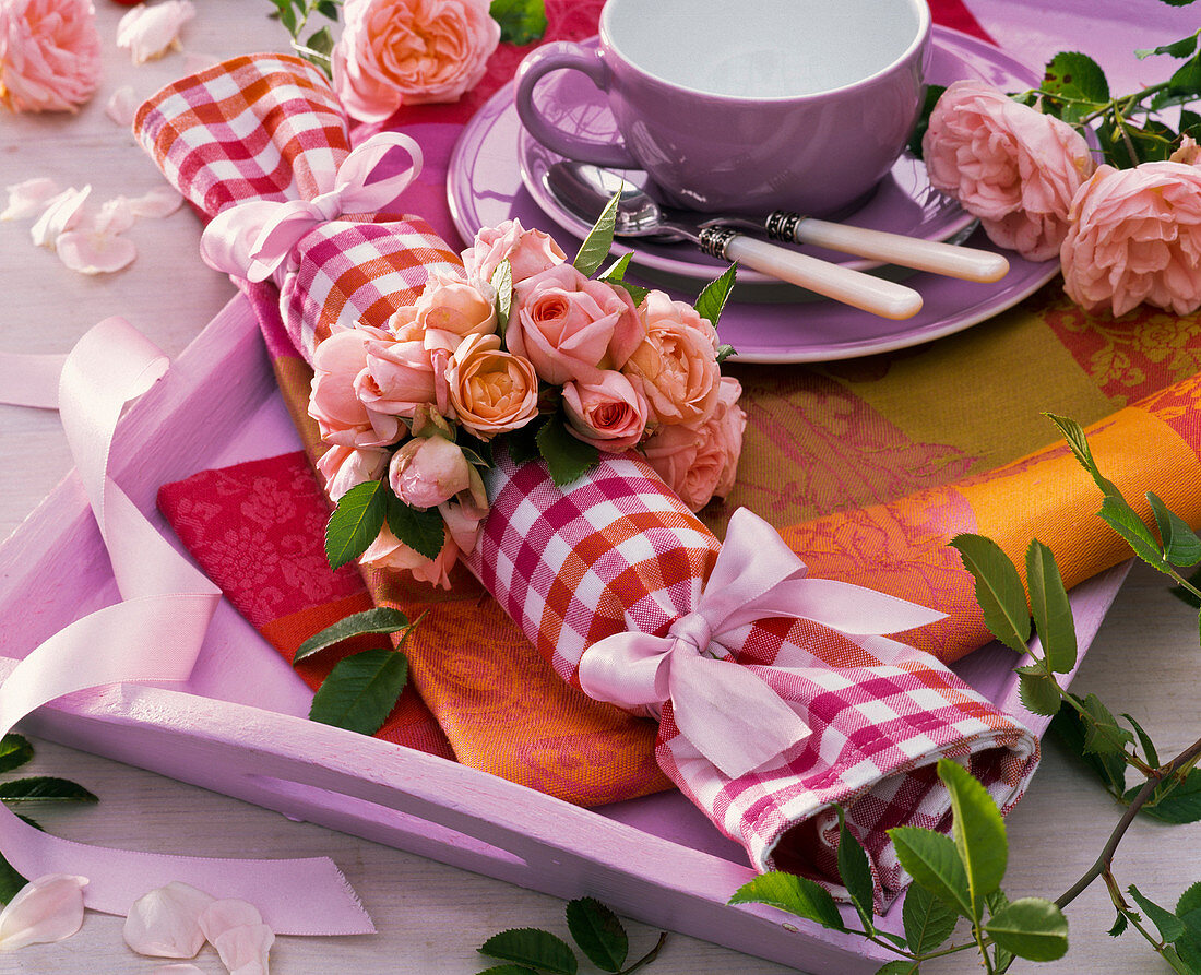 Napkin ring made of pink (roses) around checked napkin, cup, tray