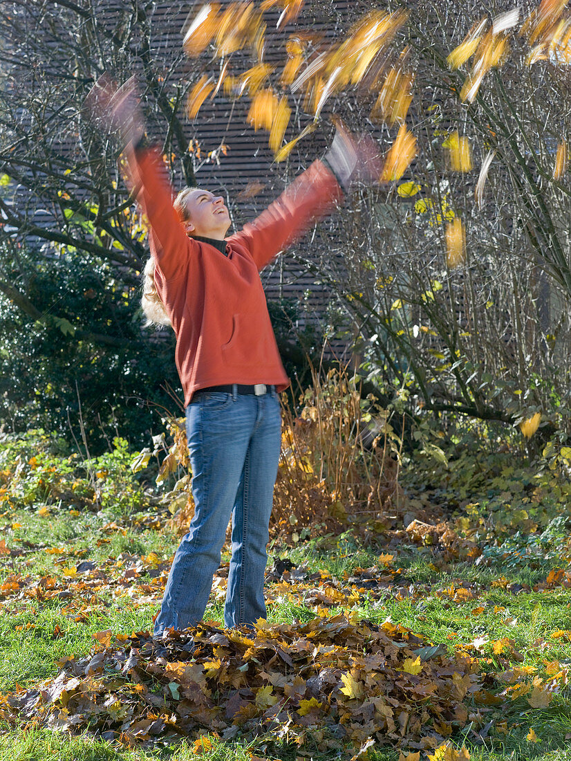 Young woman throwing leaves in the air