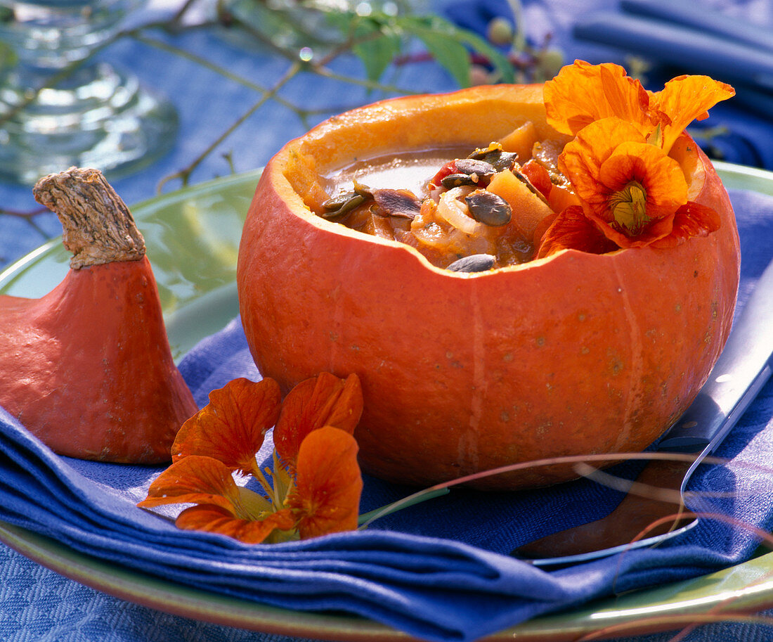 Pumpkin soup in Cucurbita (pumpkin) decorated with Tropaeolum (nasturtium)