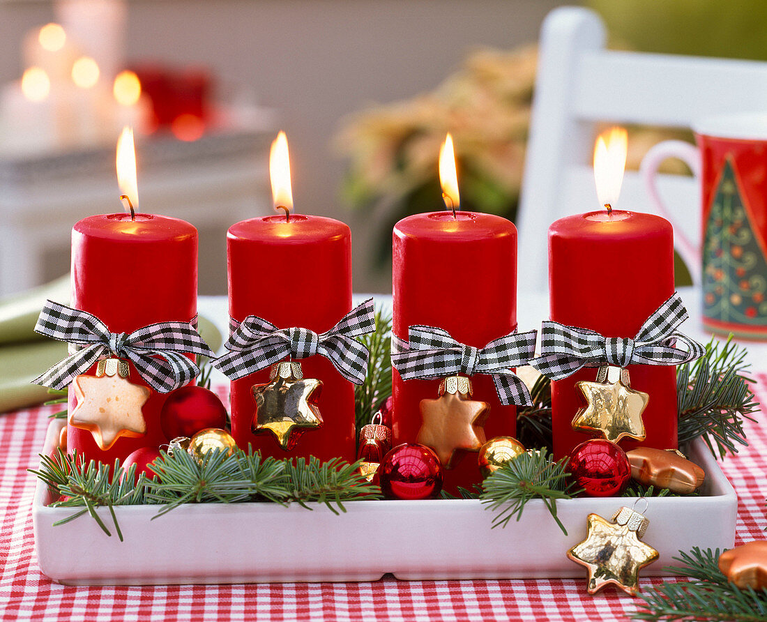 Adventskranz mit roten Kerzen, Schleifen und Weihnachtsbaumschmuck
